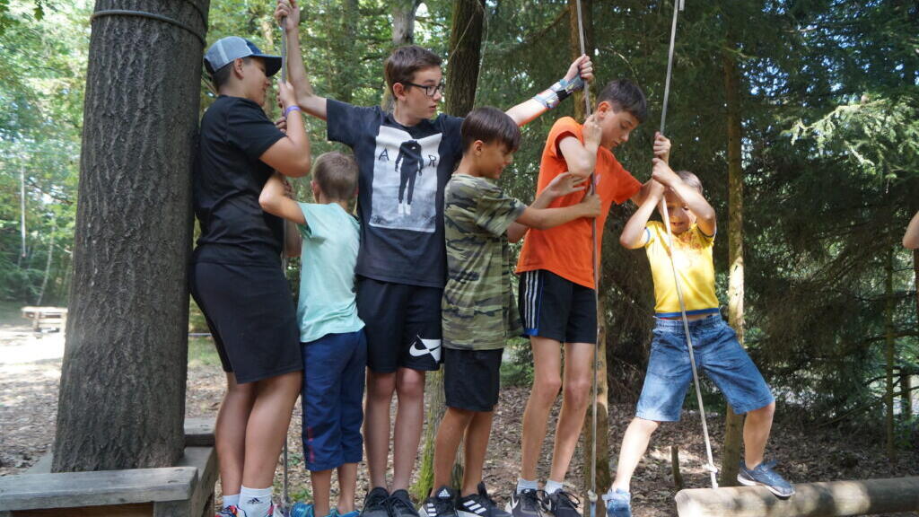Sechs Kinder und Jugendliche spielen im Seilgarten