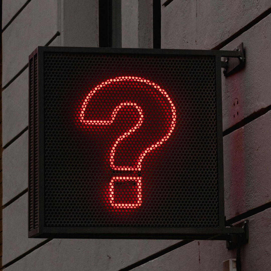 Leuchtzeichen mit rotem Fragezeichen an Häuserwand