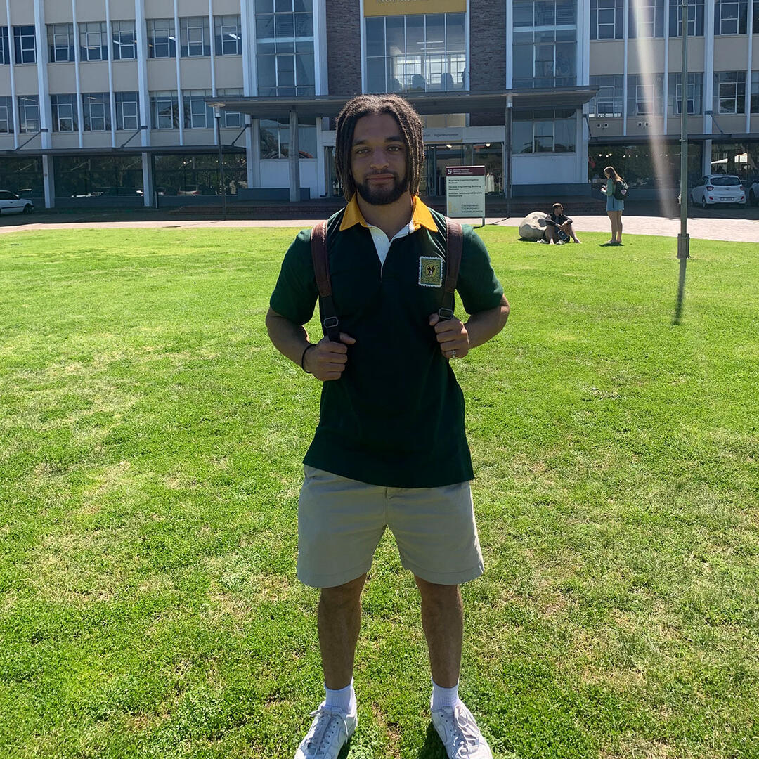 Student William auf einer Wiese vor der Universität Stellenbosch in Südafrika