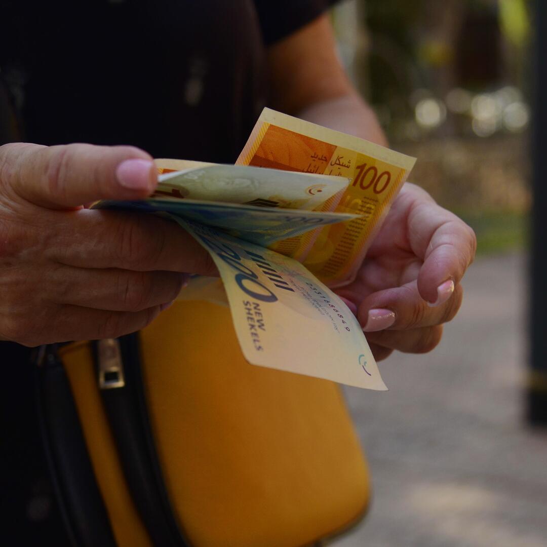 Frau hält israelische Schekel in der Hand