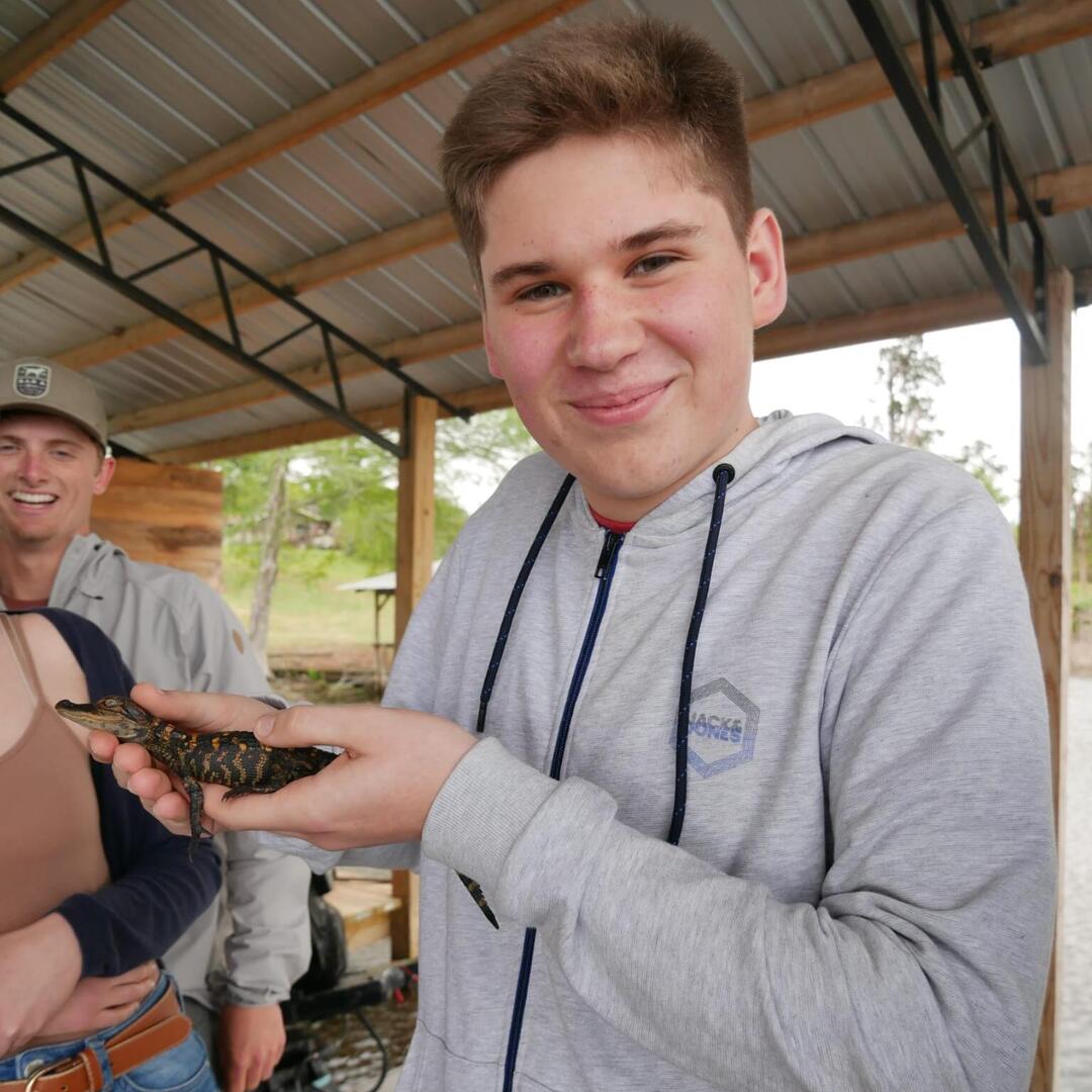Austausch-Schüler Florian hält einen kleinen Alligator in der Hand