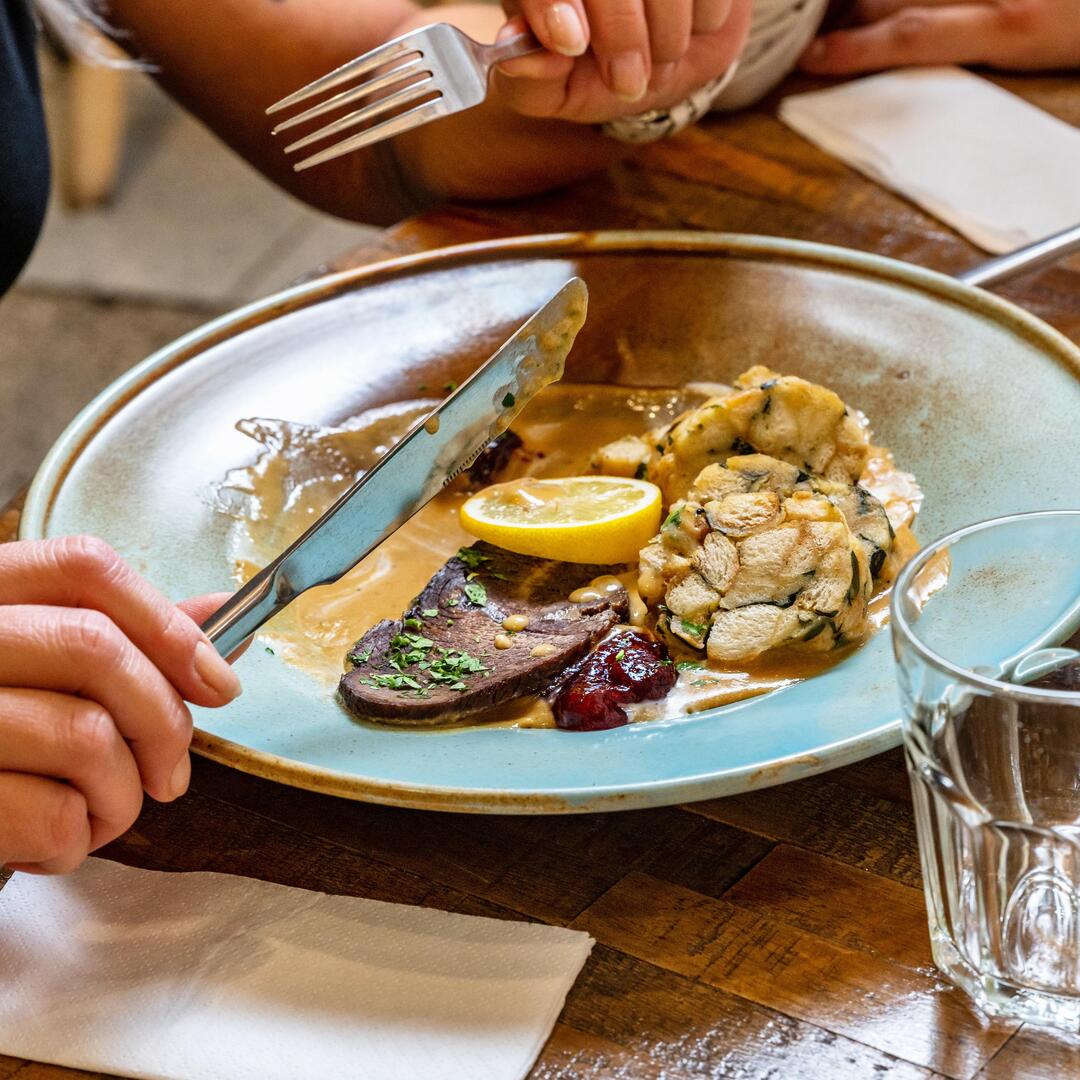 Eine Frau isst traditionell tschechisches Essen Svíčková na smetaně mit Soße, Rindfleisch und Knödel