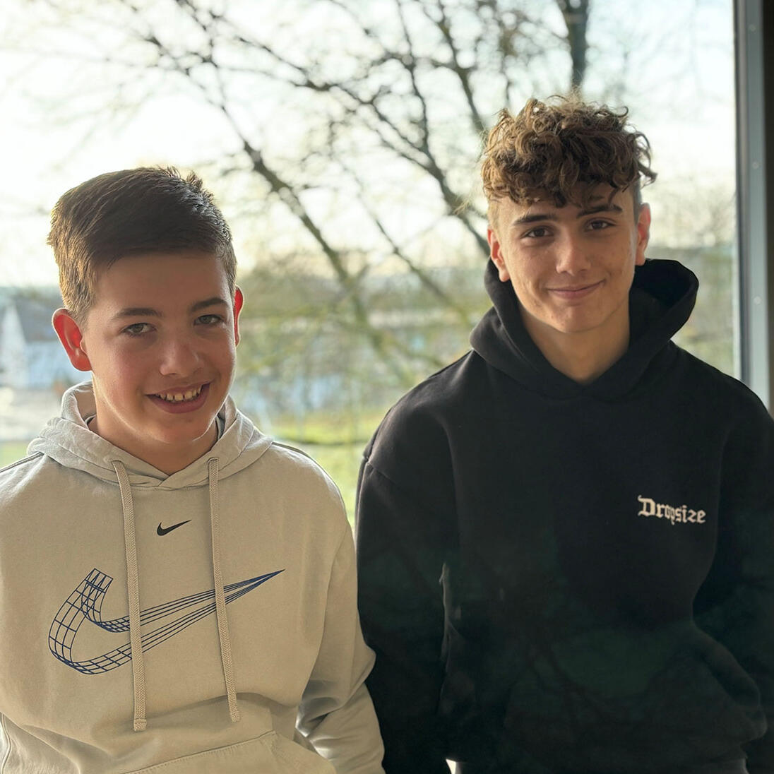 Tim und Gregor stehen vor einem Fenster in der Realschule Wemding mit Blick auf die Bäume