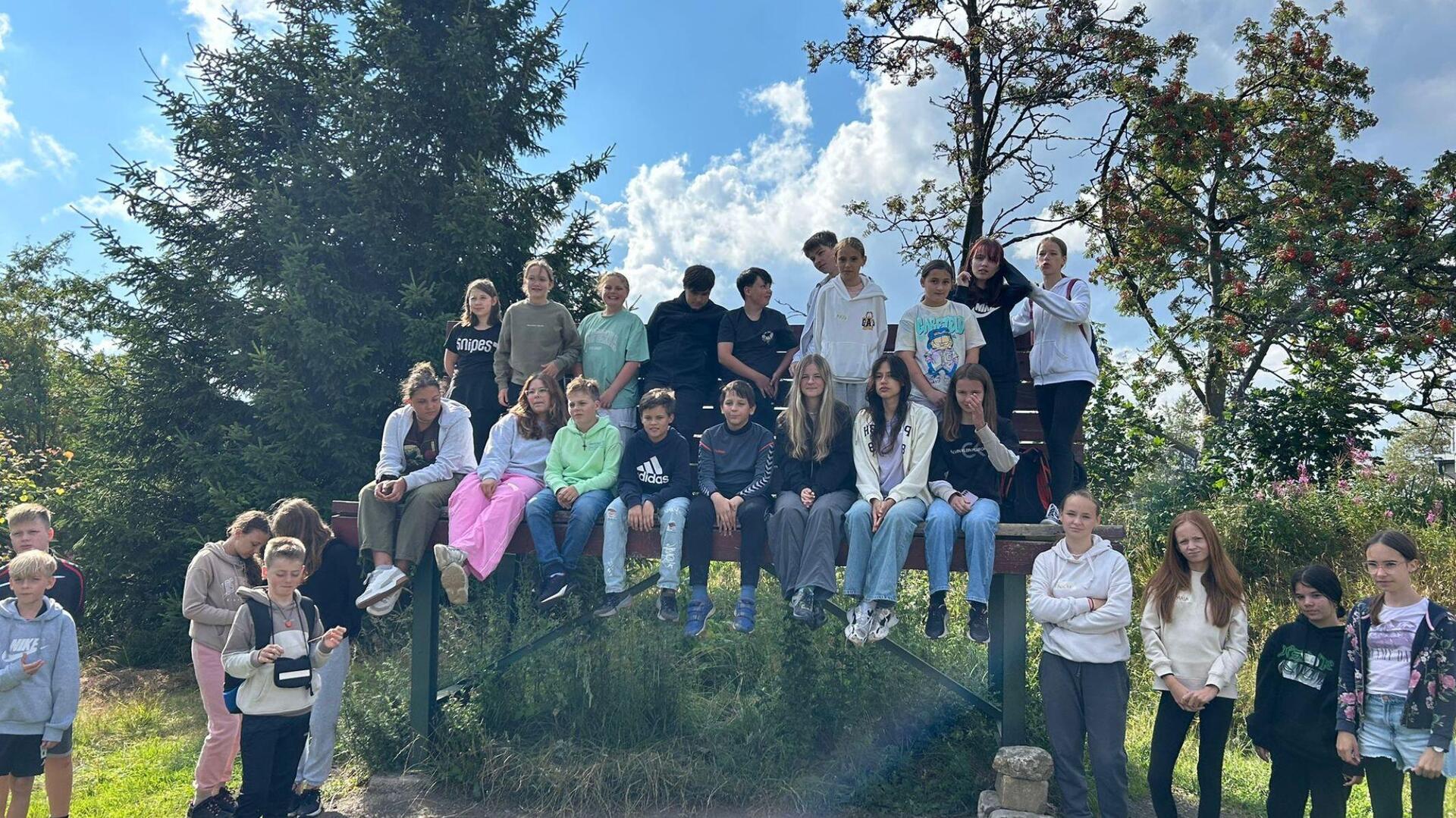 Jugendliche sitzend und stehend um und auf Holzbank