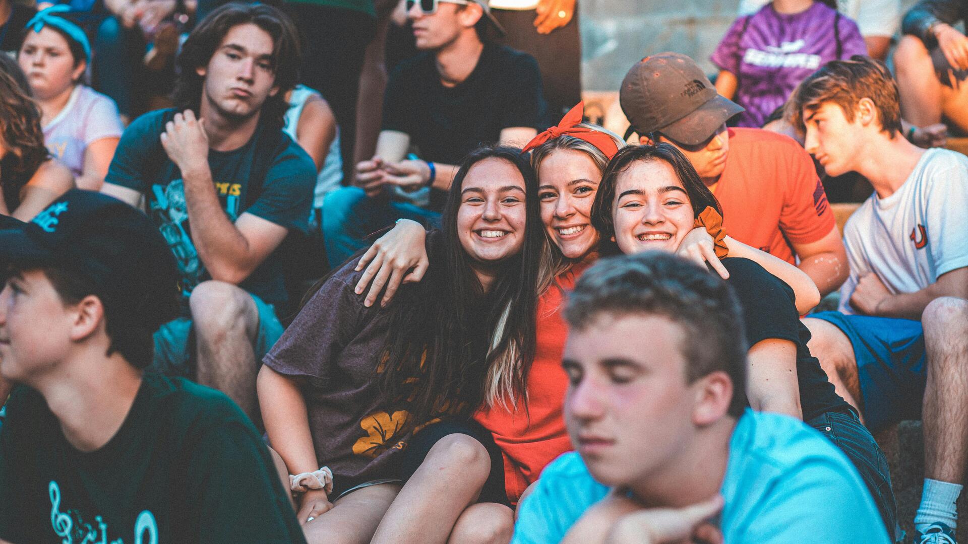 Viele junge fröhliche Menschen sitzen zusammen und umarmen sich teilweise