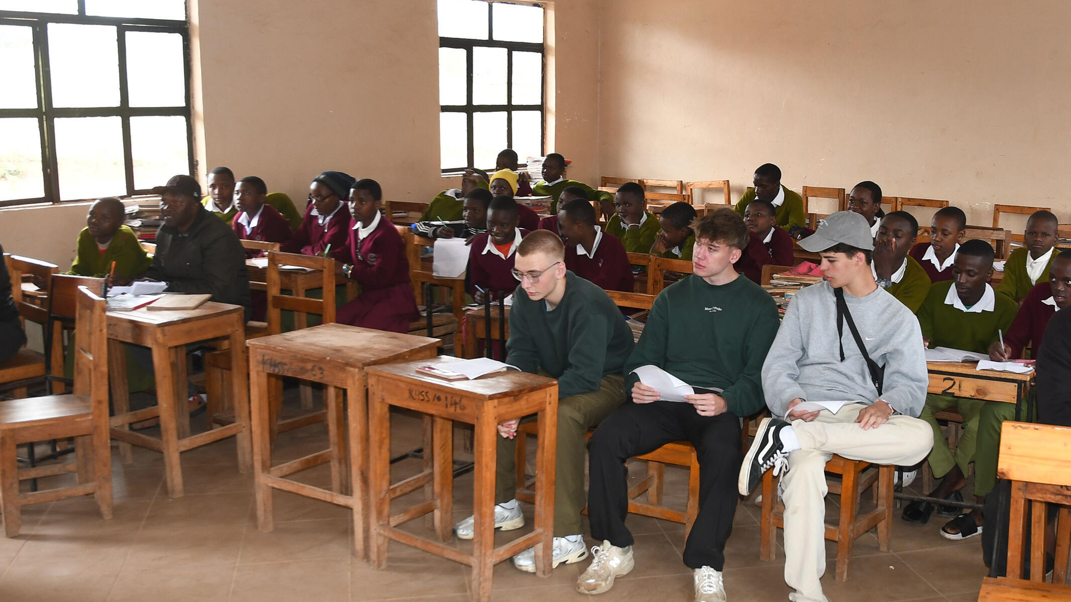 Drei bayerische Schüler sitzen im Klassenzimmer der Kihansi Secondary School in Mapanda, Tansania. 