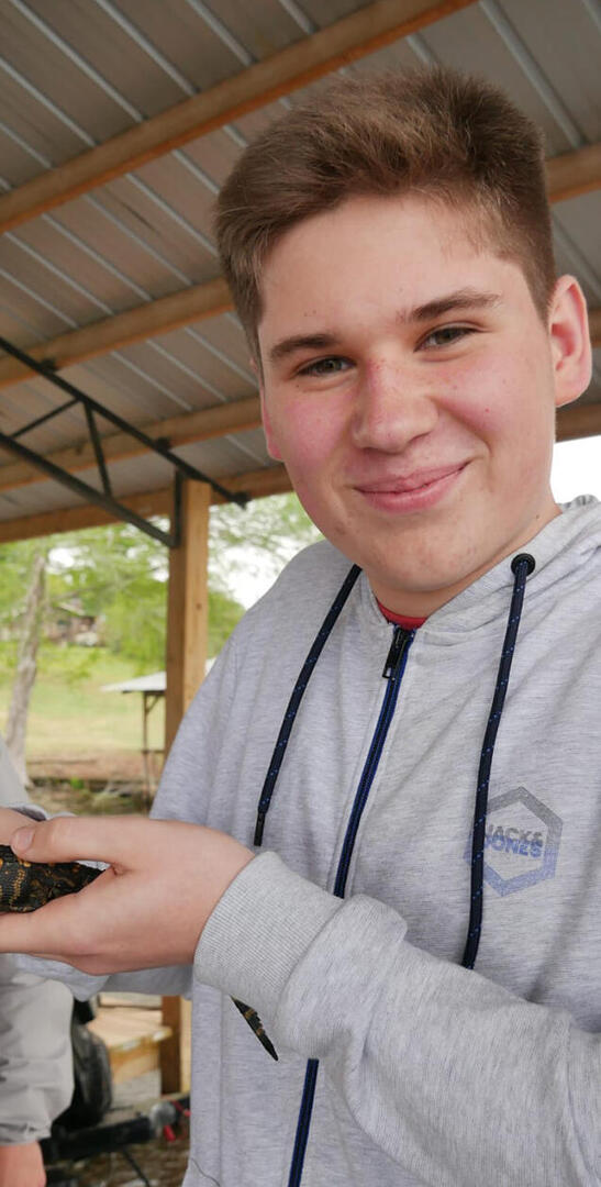 Florian hält beim beruflichen Austausch in den USA ein kleines Krokodil in den Händen