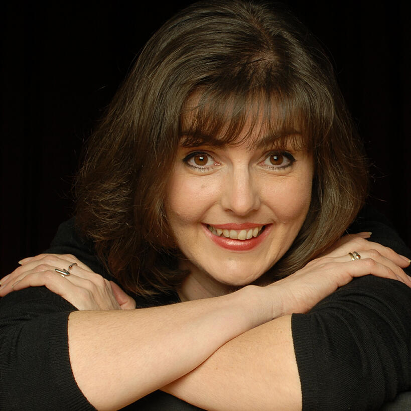 Portrait von Anne Buter mit verschränkten Armen und schwarzem Hintergrund