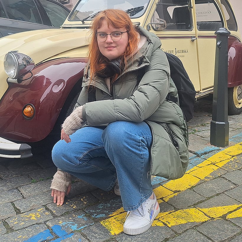 Austauschschülerin Hanna kniet vor einem Oldtimer einer tschechischen Galerie